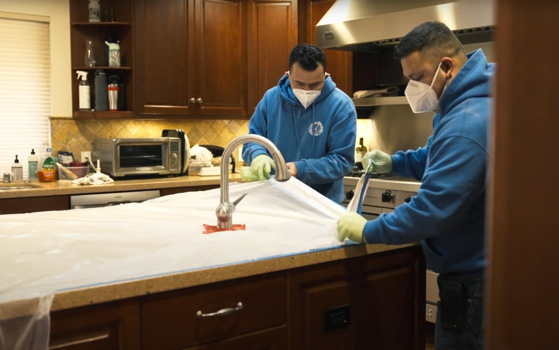 Water damage restoration professionals working in kitchen with protective equipment